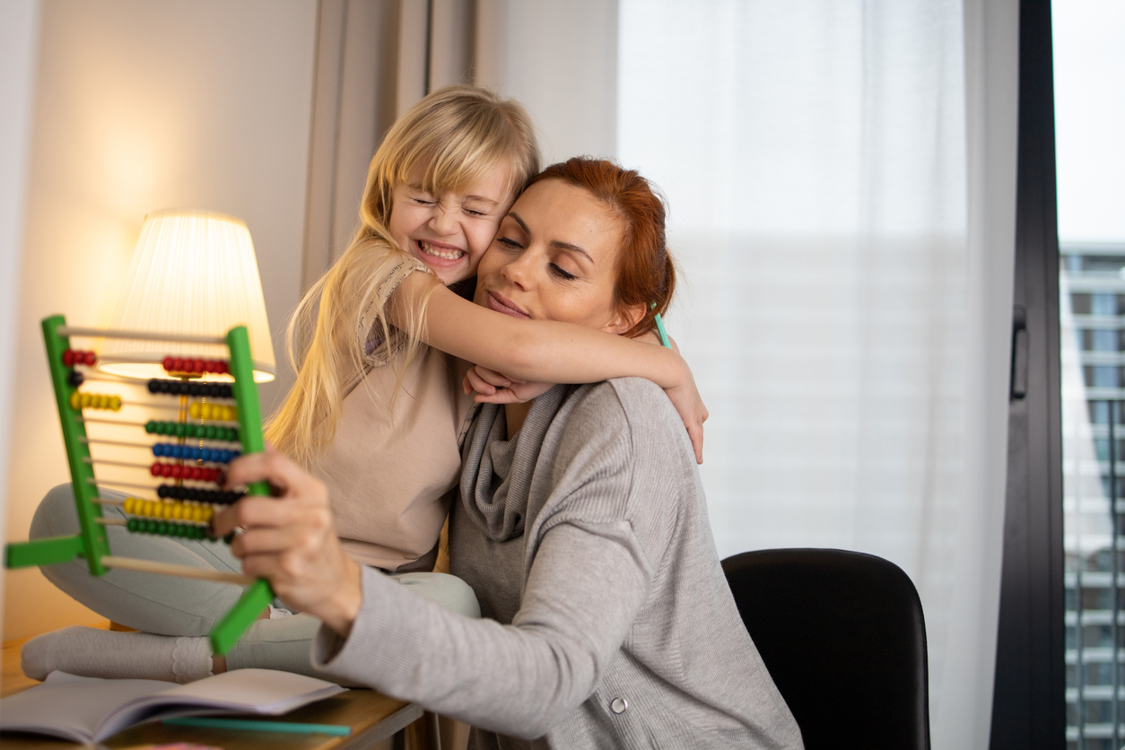 Little girl working her homework with mother